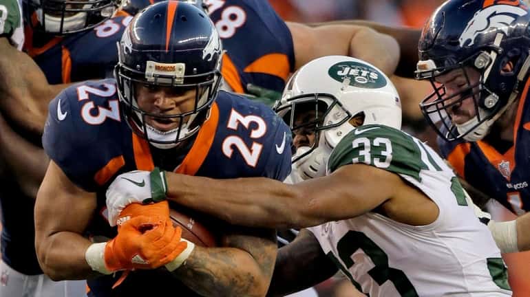 Broncos running back Devontae Booker is hit by Jets strong...