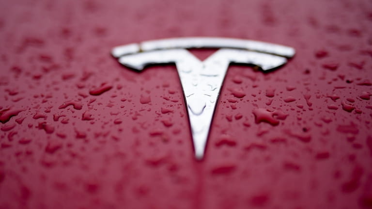 A Tesla logo has rain drops on it Feb. 27,...