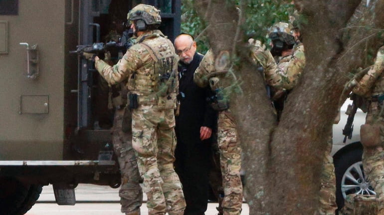 Authorities escort a hostage out of the Congregation Beth Israel...