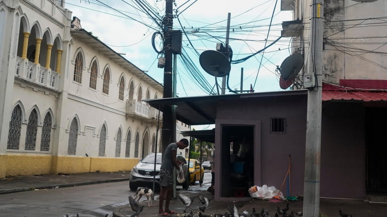 A man feeds pigeons on a street where Gilberto Hernandez,...
