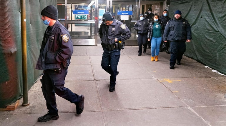NYPD members walk from a door at Harlem Hospital in...