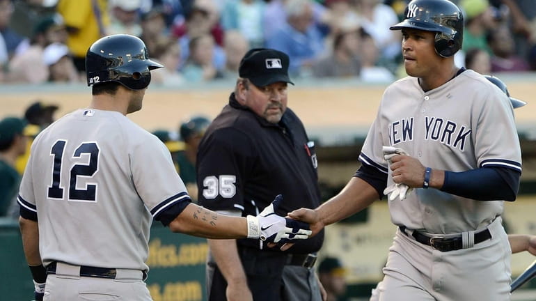 Alex Rodriguez is congratulated by Eric Chavez after Rodriguez scored...