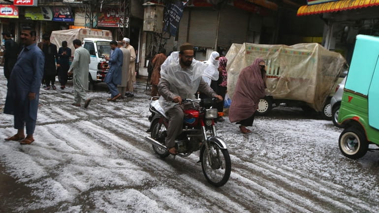People walk on the road covered by hailstones due to...