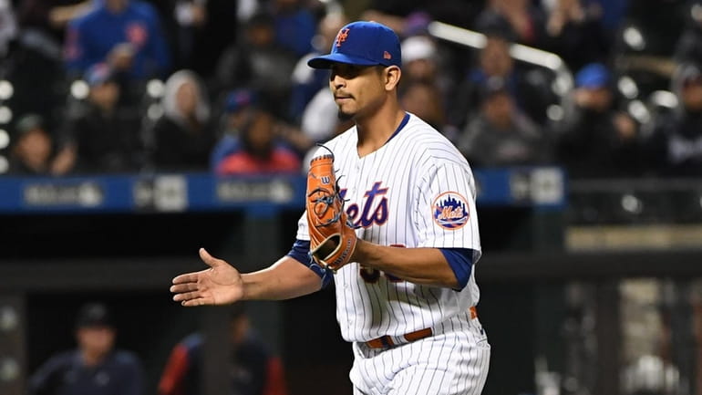Mets starting pitcher Carlos Carrasco reacts as he walks to...