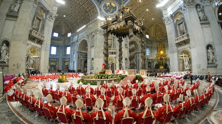 Cardinals, in red, attend a Mass for the election of...