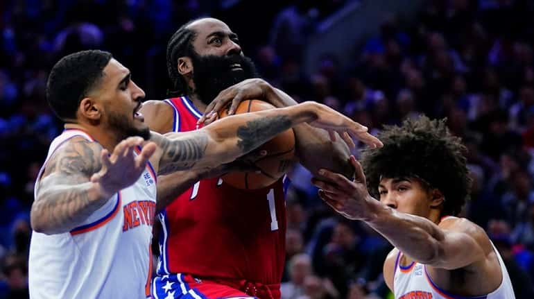 The 76ers' James Harden, center, goes up for a shot...