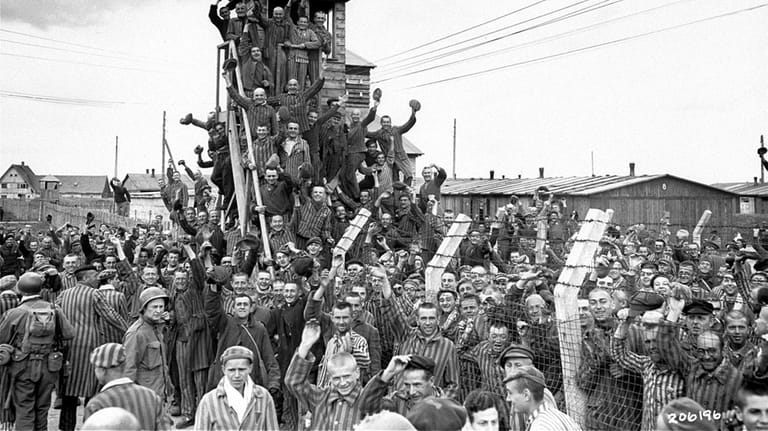 Survivors in Allach, a sub-camp of Dachau, Germany, greet arriving U.S. troops...