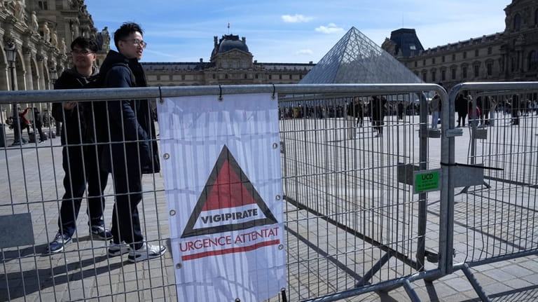 Tourist stand by a sign alerting on France's highest security...