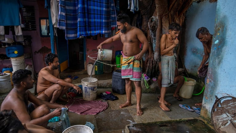 Migrant workers wash their clothes near a well which serves...