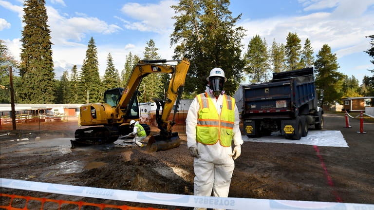 Environmental cleanup specialists work at an asbestos cleanup site in...