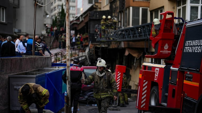 Firefighters and emergency teams work in the aftermath of a...