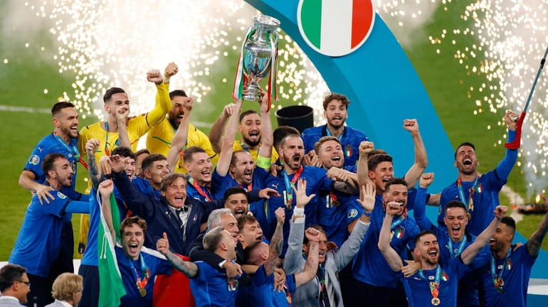 Italy's defender Giorgio Chiellini (C) raises the European Championship trophy...