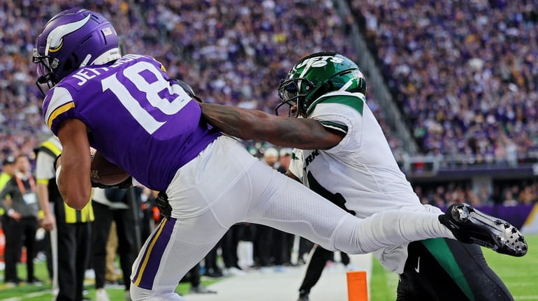 Justin Jefferson of the Vikings catches a touchdown pass while D.J....
