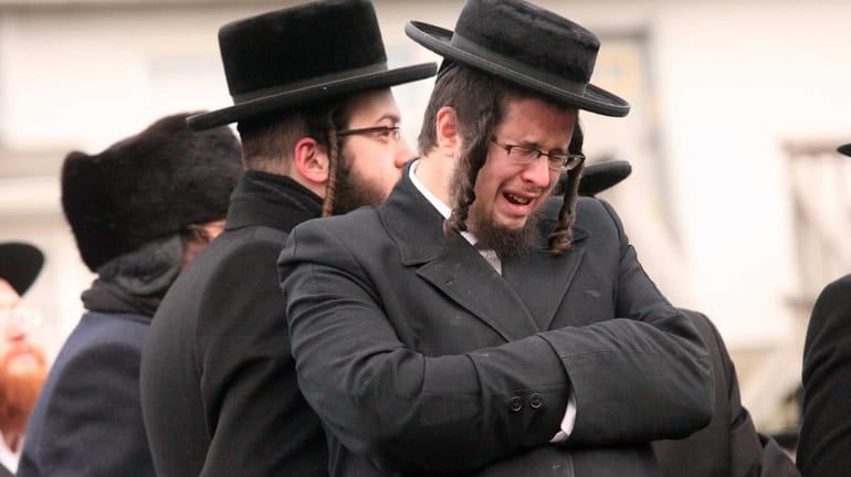 Mourners gather outside the Satmar synagogue during funeral services for...