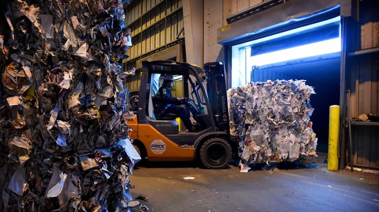 Bales of recyclable paper are loaded onto a truck on May...