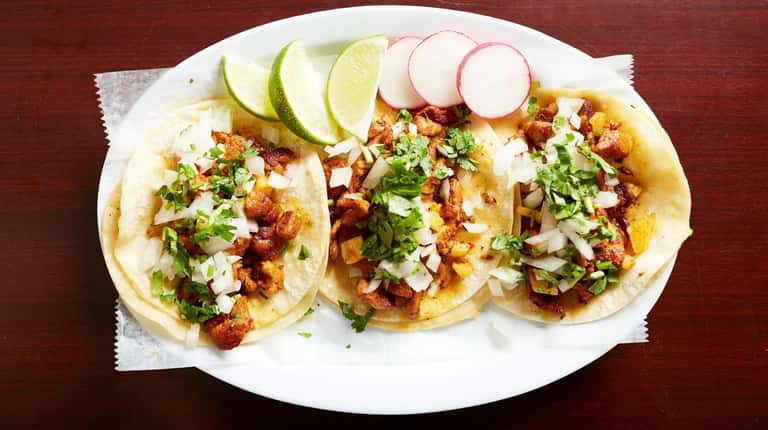 Al pastor tacos topped with cilantro and onions from Taco...
