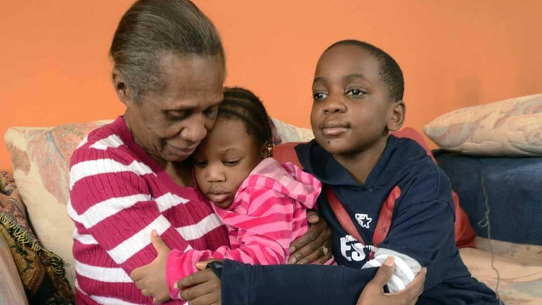 Patricia Stevens, left, hugs her grandchildren Ashely Stevens, 3, center,...