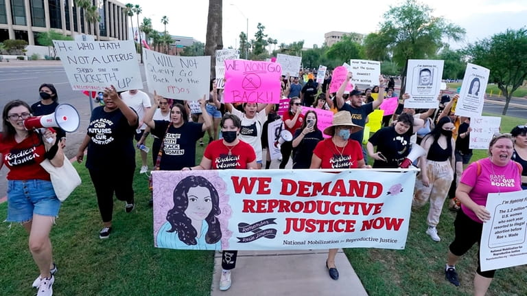 Thousands of protesters march around the Arizona Capitol in protest...