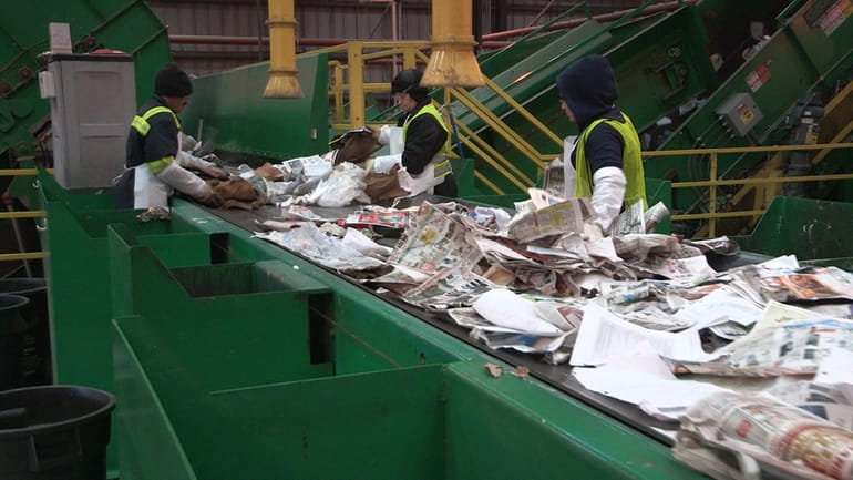 Employees sort paper at the Green Stream recycling facility in...