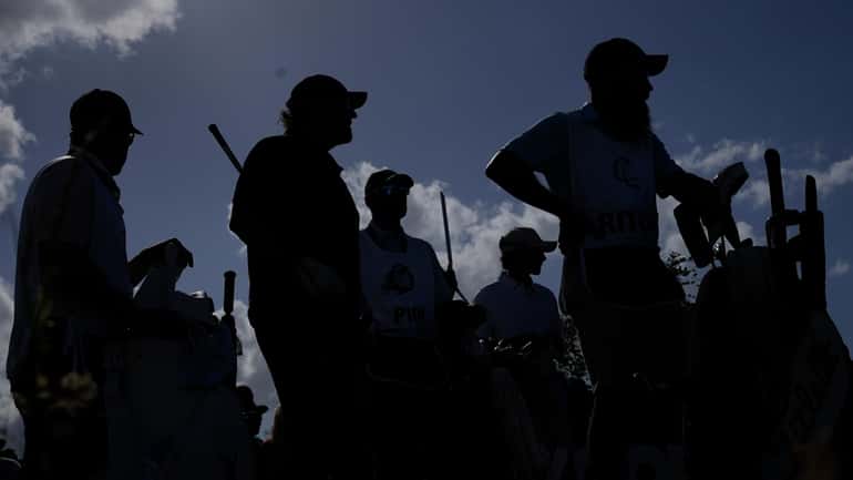 Phil Mickelson, second left, waits to play his tee shot...
