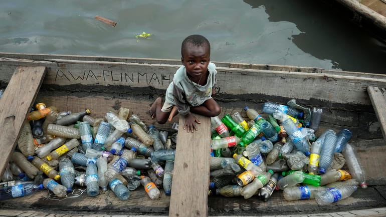 A child sits inside a canoe with empty plastic bottles...