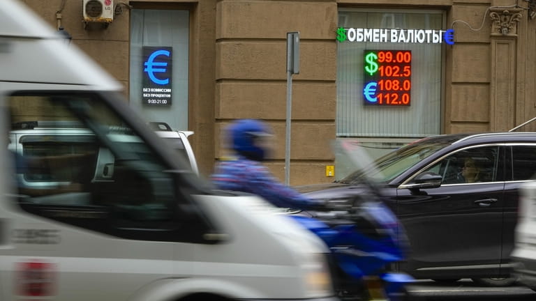 Vehicles drive past a currency exchange office in Moscow, Russia,...