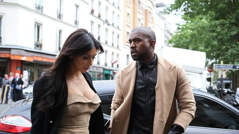 Kanye West and Kim Kardashian walk through rue Darboy as...