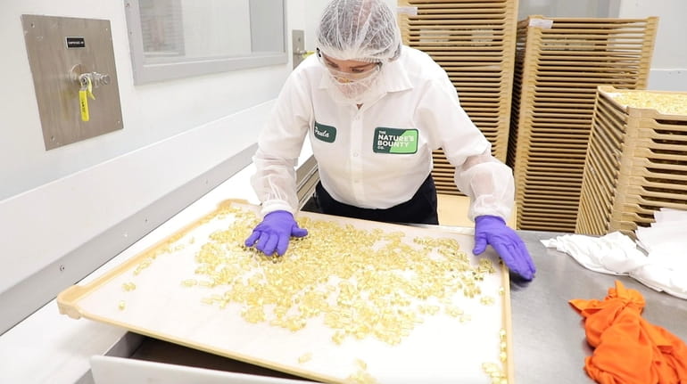 A Nature's Bounty employee works in the production area making vitamins...