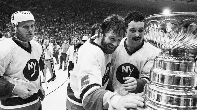Islanders captain Denis Potvin, No. 5, reaches out to touch...