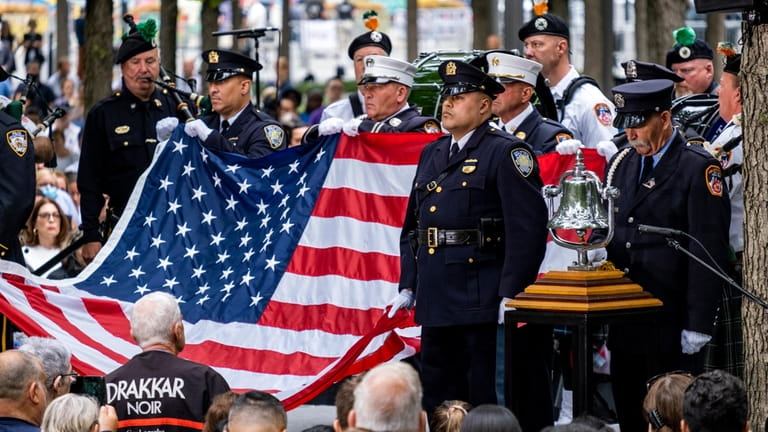 Firefighters pause Sunday in lower Manhattan after the ringing of...