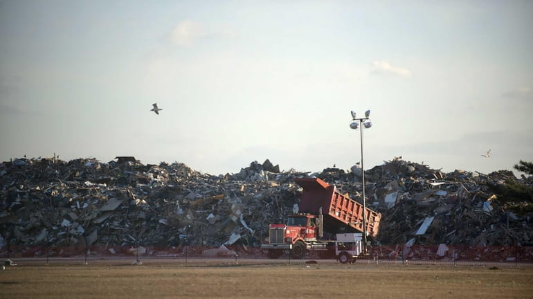 Debris from superstorm Sandy is dumped at a temporary collection...