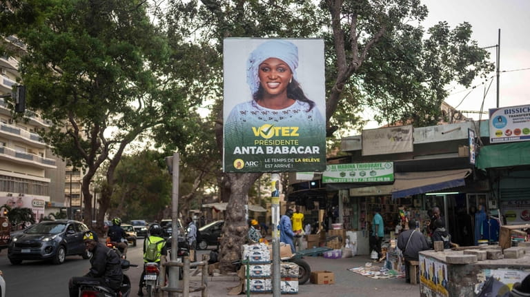 People walk past an electoral banner of Anta Babacar, the...