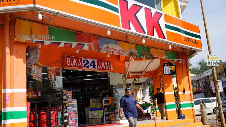 A customer walk out from KK Mart convenience store in...