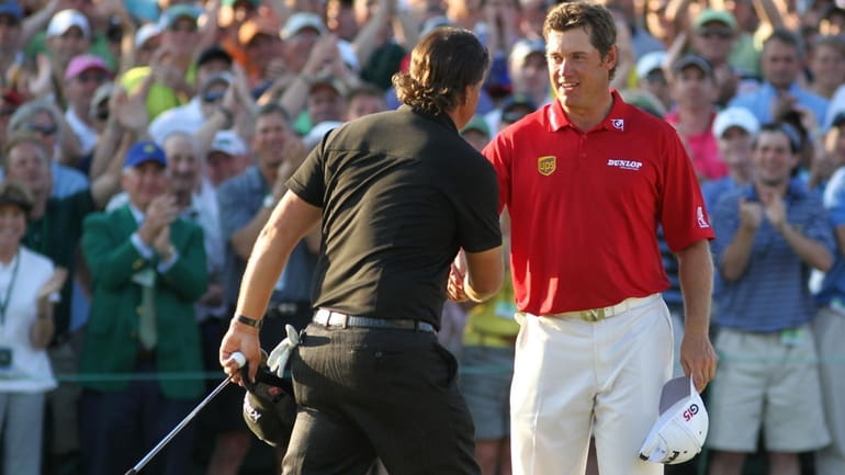 Phil Mickelson (L) shakes hands with Lee Westwood of England...