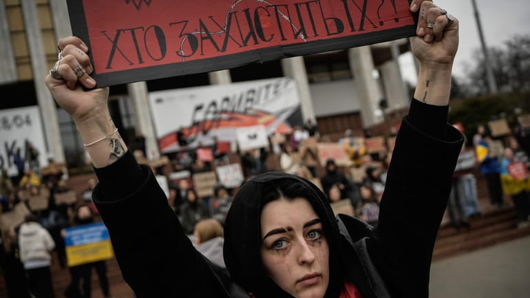 A woman holds a sign during a protest in Kyiv,...