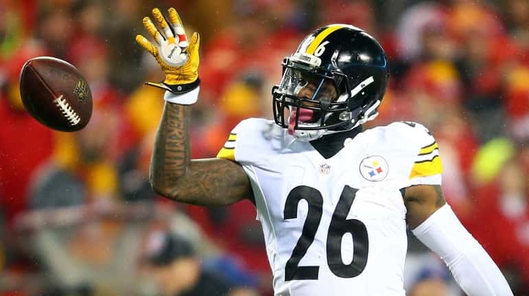 Then-Steelers running back Le'Veon Bell tosses the ball forward after gaining...