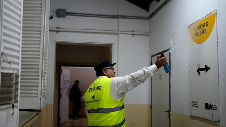 A guard sprays insecticide inside a hospital area where patients...