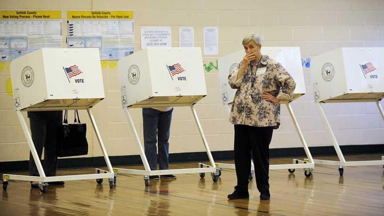 A voting inspector stands by while voters cast their ballot...