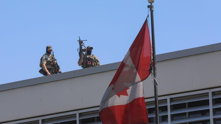 Canadian soldiers stand guard on the rooftop of their embassy...