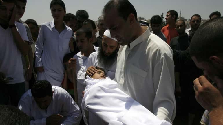 A relative holds the body of 6-year-old Syrian boy Bilal...