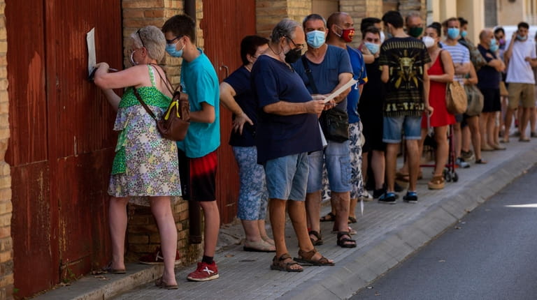 People wearing face masks queued up Monday to be tested...