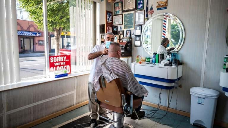 Sal Bademci works on a customer at his barbershop on...