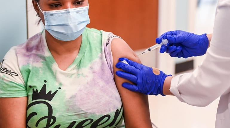 Maria Rojas Reyes, of Roosevelt, receives a COVID-19 vaccine from...