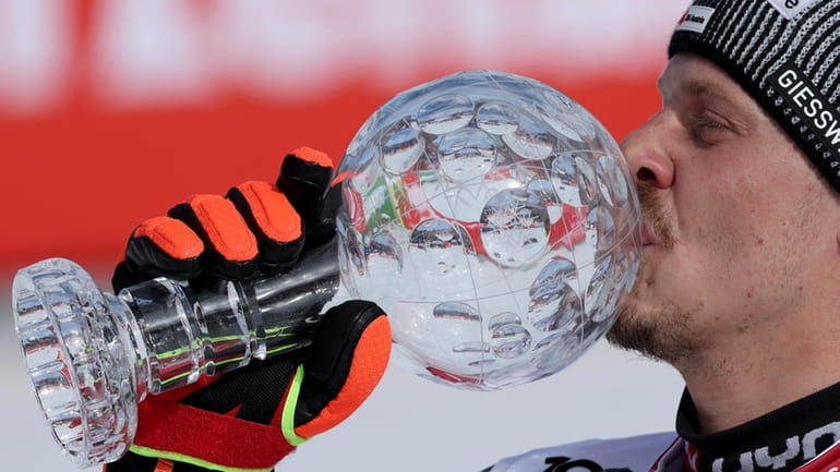 Austria's Manuel Feller kisses the trophy for the alpine ski,...