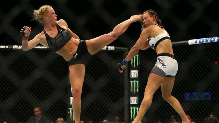 UFC bantamweight champion Holly Holm, left, kicks Miesha Tate takes...