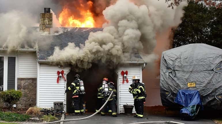 Firefighters battle a Farmingville house fire on Friday, Dec. 22,...