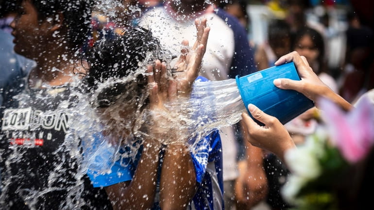 A man reacts as a bucket of water is splashed...