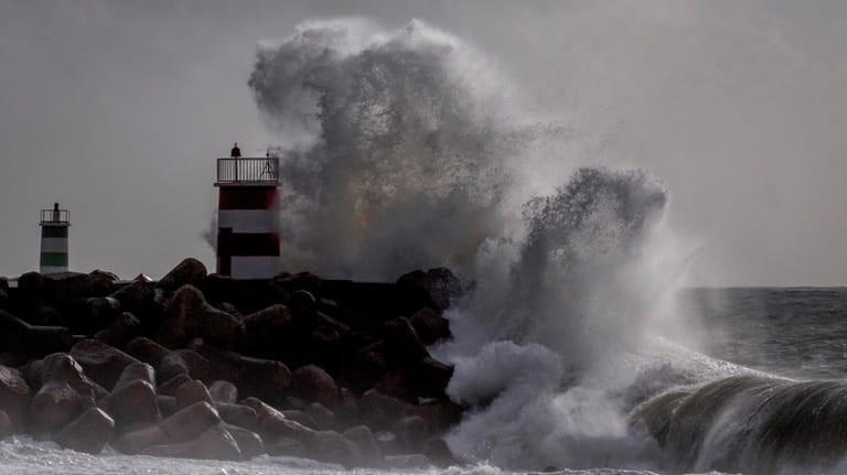 Big waves crash against a light house in Nazare, Portugal,...