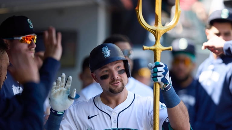 Seattle Mariners catcher Cal Raleigh celebrates in the dugout after...