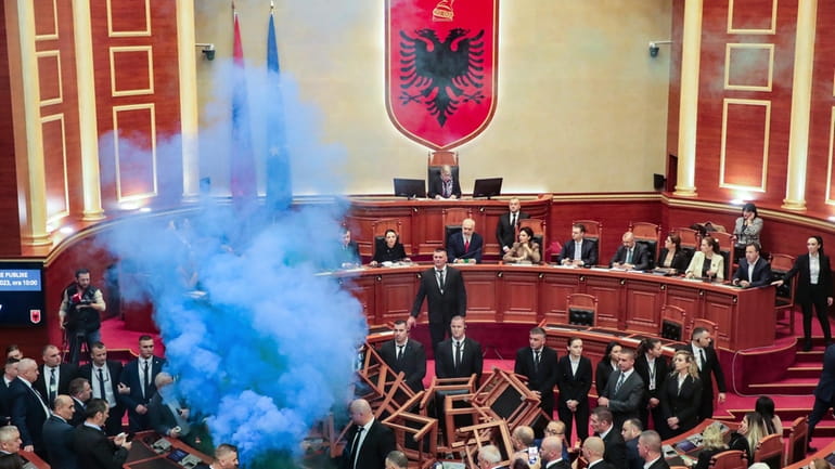 Democratic lawmakers throw flares during a parliament session in Tirana,...